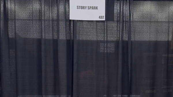 Booth with Story Spark sign with black curtains