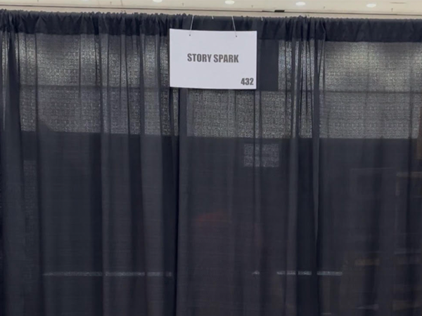 Booth with Story Spark sign with black curtains