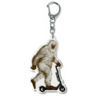 Acrylic keychain with Bigfoot riding a scooter on a white background