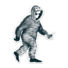 A die-cut sticker featuring a black and white graphic illustration of an alien wearing a Bigfoot suit and holding a remote control, shown on a plain white background.