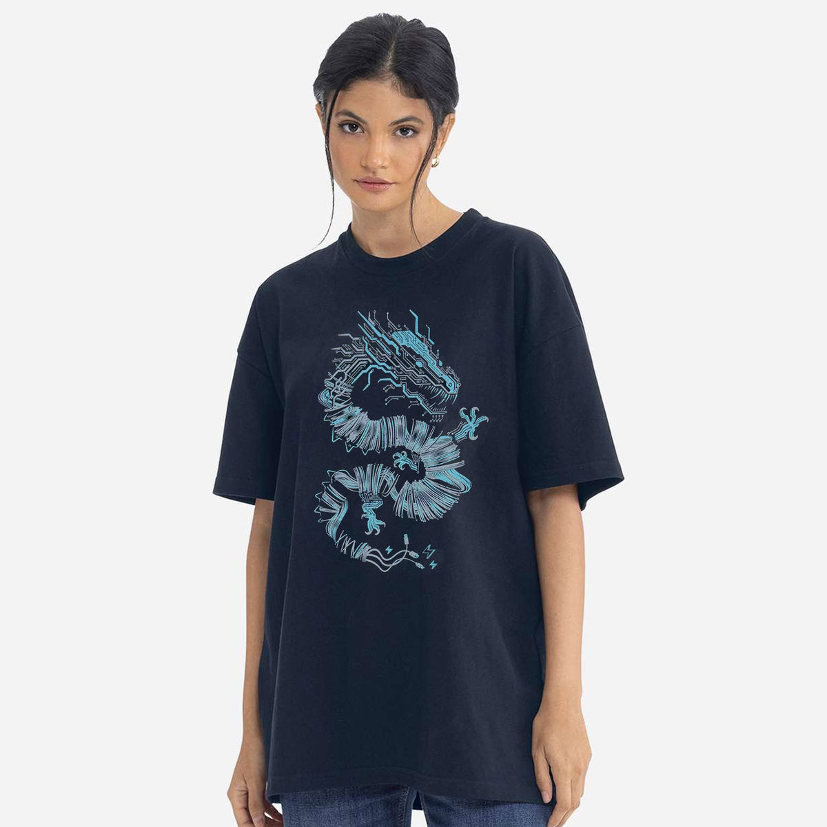 A woman modeling an oversized dark navy t-shirt with a light blue dragon graphic printed on the front, set against a plain light gray background. Graphic designed by STORY SPARK